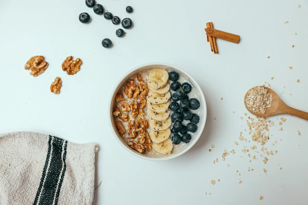 Desayuno con yogur, avena y fruta junto a una libreta